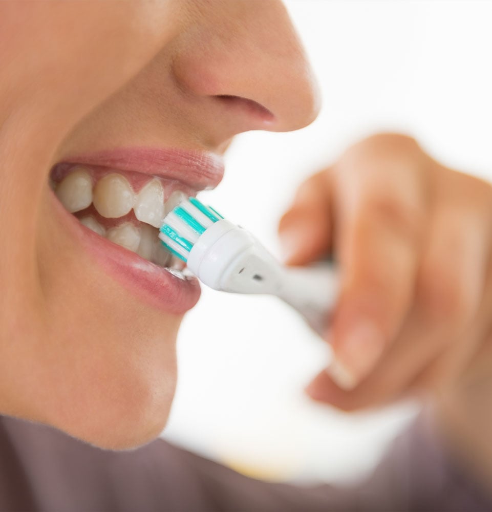 Closeup on young woman brushing teeth
