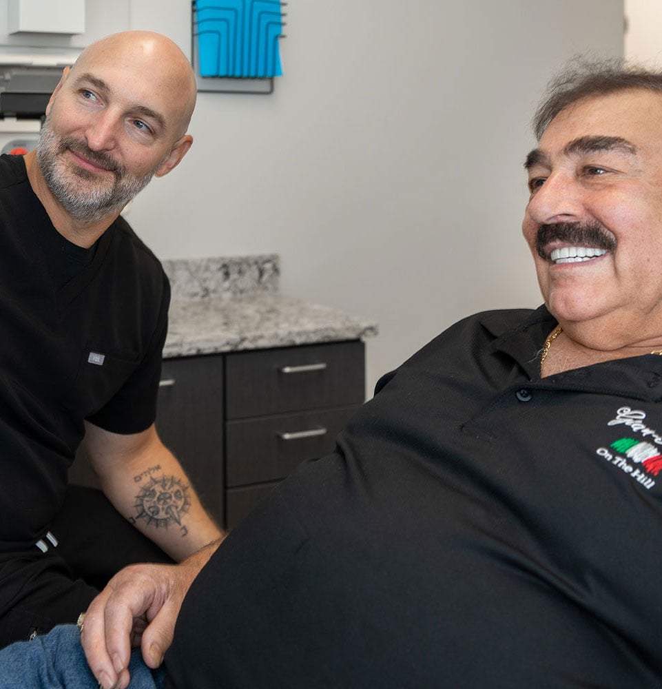 doctor and patient smiling brightly while going over dental procedure information